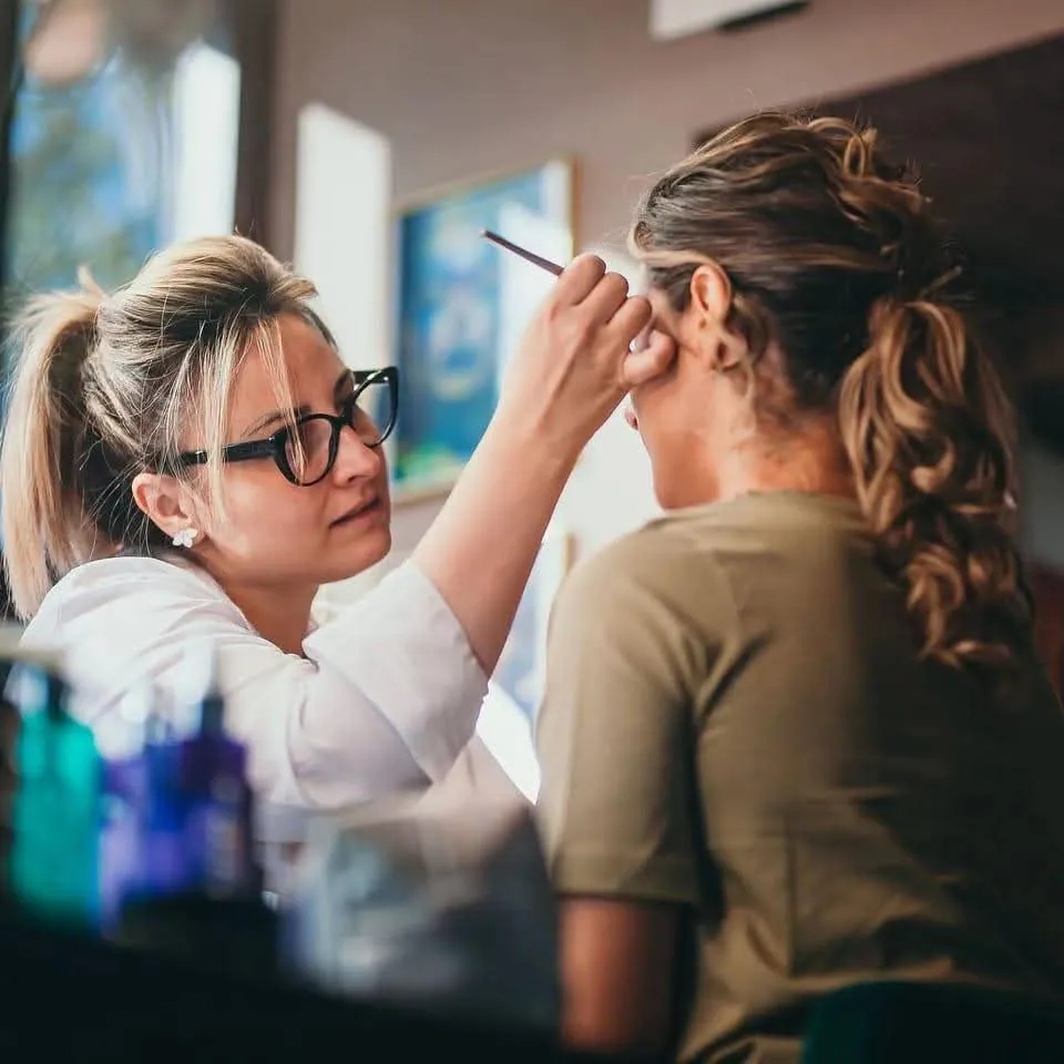 Corina Crețu aplică machiajul unei cliente cu pensula